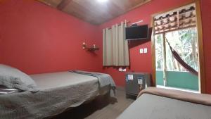 a red bedroom with two beds and a window at Chalés Guigó-Cumuruxatiba in Cumuruxatiba