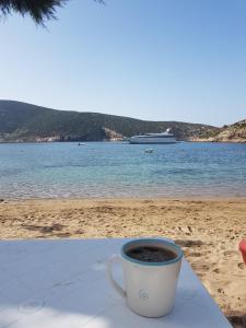 a cup of coffee sitting on a table on the beach at Captain Yannis in Sifnos