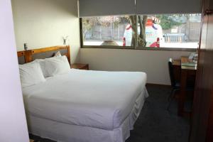 a bedroom with a large white bed and a window at Hotel Mar Andino in Rancagua