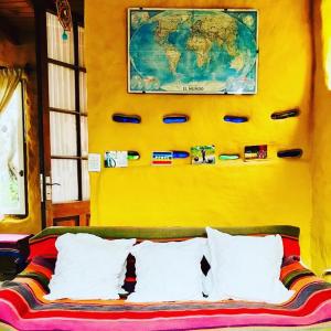 eine gelbe Wand mit einer Weltkarte über einem Bett in der Unterkunft Todo se transforma in Cuchilla Alta