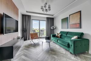 salon z zieloną kanapą i stołem w obiekcie Nadmorze by Q4Apartments w Gdańsku