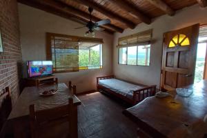 a living room with a table and a bed and a television at fatima cabaña 4personas in Villa de Las Rosas