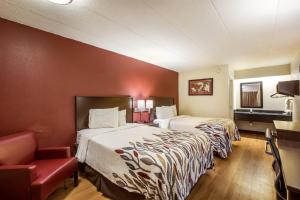 a hotel room with two beds and a chair at Red Roof Inn Saginaw – Frankenmuth in Saginaw