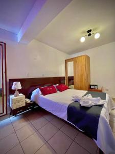 a bedroom with a large bed with red pillows at Hotel Feimar in Cusco