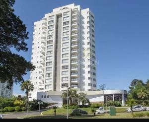 un edificio blanco alto con coches estacionados frente a él en Torre Amadeus 203, en Punta del Este