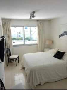 1 dormitorio con 1 cama, 1 silla y 1 ventana en Torre Amadeus 203, en Punta del Este