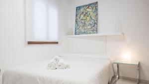 a white bedroom with a bed and a table at Casa Recogidas - Apartamentos Aloha Toledo in Toledo