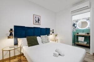 a bedroom with a large white bed with a blue headboard at Malaga City Suites in Málaga