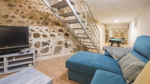 Una sala de estar con un sofá azul y un televisor. en El Patio del Arrayán - Apartamentos Aloha Toledo, en Toledo