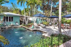 沃思湖Art Deco Apt w Pool One Mile to Beach Pets Welcome的一个带椅子和遮阳伞的游泳池以及一座房子