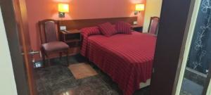 Habitación de hotel con cama roja y escritorio. en Arenas Calidas en Las Grutas