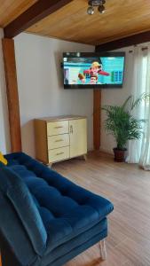 a living room with a blue couch and a flat screen tv at La Casa de Tita _ Usiacuri in Usiacurí