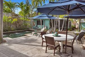 a patio with a table and chairs and an umbrella at Charming Studio w Pool One Mile to Beach Pets Welcome in Lake Worth