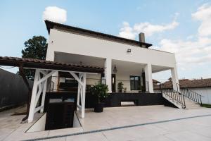 a white house with a porch and stairs at Pensiunea Magnesia (4 margarete****) in Sânâteşti