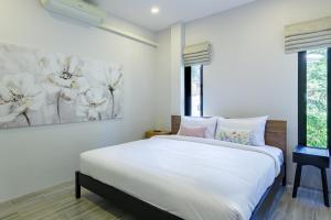 ein Schlafzimmer mit einem weißen Bett und einem Gemälde an der Wand in der Unterkunft Villa primor Chaloklum Koh phangan in Chaloklum