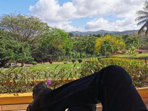 una persona sentada en un banco mirando hacia un parque en Hotel Puerto San Luis, en Tilarán