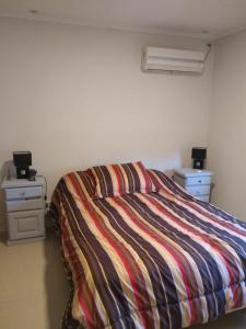 a bedroom with a bed with a colorful striped bedspread at Apartamentos Laguna de Navarro in Navarro