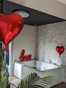 bañera en una habitación con corazones en la pared en Gite Romantique avec Espace Balnéo et Ciel Etoilé "La Maison du Bonheur Saint Germer de Fly" Nuit Romantique Oise, Picardie, Normandie en Saint-Germer-de-Fly