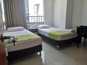 two beds in a room with a window at Habitar de Asis in Bucaramanga