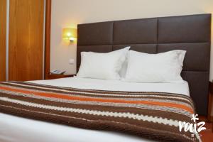 a large bed with a brown headboard and white pillows at Raiz Alentejana II in Reguengos de Monsaraz