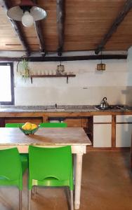 a kitchen with a wooden table and green chairs at Casita campestre in Cacheuta