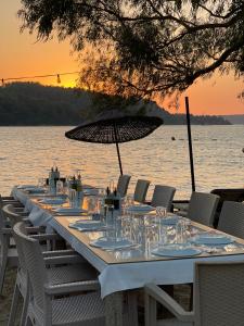 a long table with chairs and an umbrella on the water at Marimare Beach & Bungalow in Marmaris