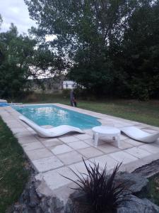 a swimming pool with two chairs and a table at Casita campestre in Cacheuta