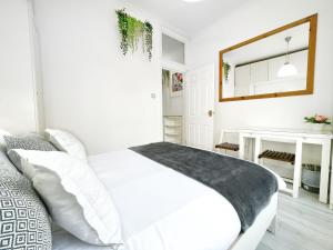 - une chambre blanche avec un lit blanc et un miroir dans l'établissement LUXURIOUS Terrace 2 Bedrooms in Relaxing Covent Garden Apartment, à Londres