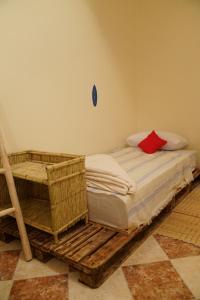 1 dormitorio con cama de madera y almohada roja en Bayti surf hostel, en Agadir