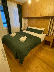 a bedroom with a large bed with two towels on it at Jahorina Woods - na stazi, ski-to-door in Jahorina