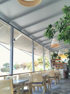 zona de comedor con mesas, sillas y ventanas en Le Grand Bleu Studios & Apartments, en Lefkos Karpathou