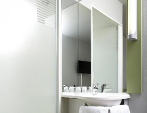 a bathroom with a sink and a mirror at ibis budget Aachen Raeren Grenze in Raeren