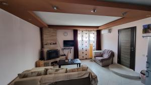 un soggiorno con divano, sedia e TV di Vila Bjelasica a Kolašin