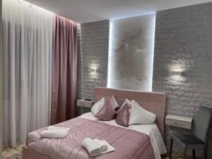 a bedroom with a pink bed with two towels on it at Residenza N&D Luxury in Bari