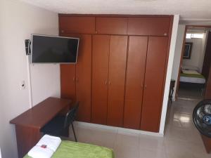 a bedroom with a desk and a tv and a cabinet at Habitar de Asis in Bucaramanga