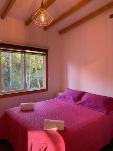 a bedroom with a purple bed with two towels on it at Cabaña El Caballo Blanco in Llanquihue