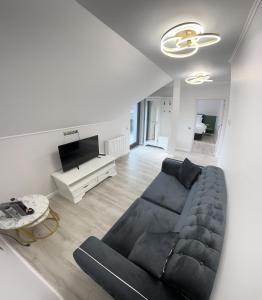 a living room with a black couch and a tv at Glam Studios in Sibiu