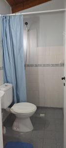 uma casa de banho com um WC e uma cortina de chuveiro azul em La casita em El Calafate
