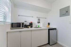 a white kitchen with a microwave and a sink at Great Studio Residence 15 min from the beach in Miami +6 photos