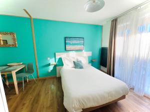 um quarto com uma cama branca e uma parede azul em Studio avec piscine aux portes d’Honfleur em Honfleur