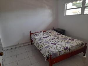 - une chambre dotée d'un lit avec un couvre-lit floral dans l'établissement FLEURIE, à Gourbeyre
