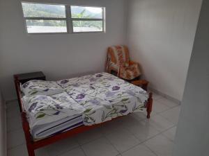 - une chambre avec un lit, une chaise et une fenêtre dans l'établissement FLEURIE, à Gourbeyre