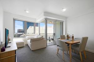a living room with a table and a couch and a dining room at The Alexander Apartments - Harbour Views, Parking, Pool, 24hr Concierge in Sydney