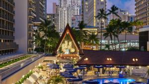 ホノルルにあるOUTRIGGER Reef Waikiki Beach Resortのテーブルとパラソル付きのリゾートの景色を望めます。