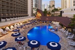 OUTRIGGER Reef Waikiki Beach Resort في هونولولو: اطلالة علوية على مسبح الفندق مع المظلات الزرقاء