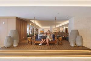 a woman and child sitting on a bench on a deck at OUTRIGGER Reef Waikiki Beach Resort in Honolulu