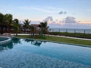 a swimming pool with a playground next to the ocean at Cantinho Vista Mar in Itacimirim