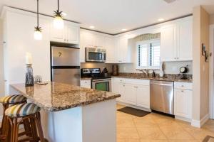 a kitchen with white cabinets and a granite counter top at SANDPIPER BEACH 205 in Sanibel