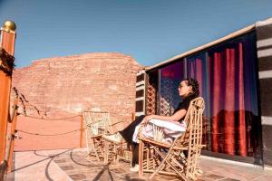 a woman sitting in a chair on a balcony at Wadi Rum Sky Tours & Camp in Wadi Rum