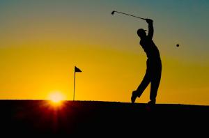 Um homem a bater numa bola de golfe ao pôr-do-sol. em Exclusive Villa at La Sella Resort em Pedreguer
